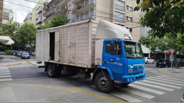 Camión azul de Mi Mudanza con caja cerrada circulando por la ciudad